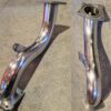 Polished stainless steel exhaust manifold on a textured surface.