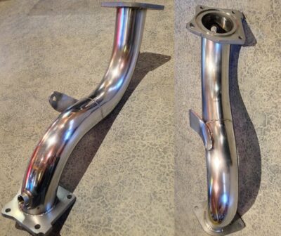 Polished stainless steel exhaust manifold on a textured surface.