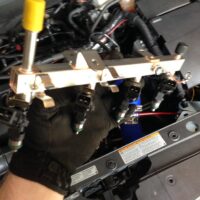 Mechanic installing a fuel injector rail into a car engine.