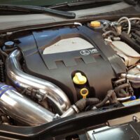 Engine bay of a vehicle with a visible v6 engine cover and aftermarket modifications.